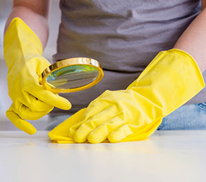 Gloved hands inspecting counter with magnifying glass